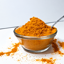 Load image into Gallery viewer, Bright orange nvigorate organic freeze-dried seabuckthorn berry powder in a clear glass bowl with a spoon and a sprinkling of powder on a white surface.